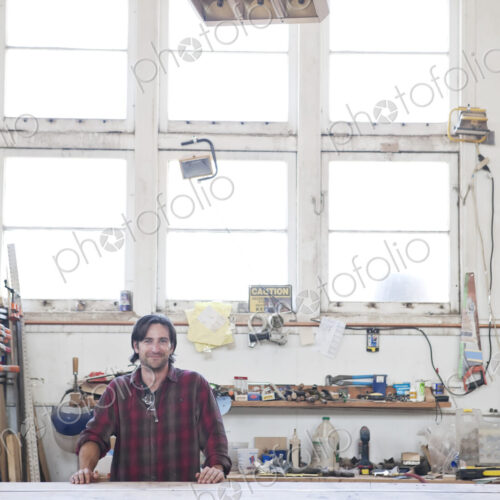 View of a caucasian man factory worker wearing safetly glasses in a woodworking factory.