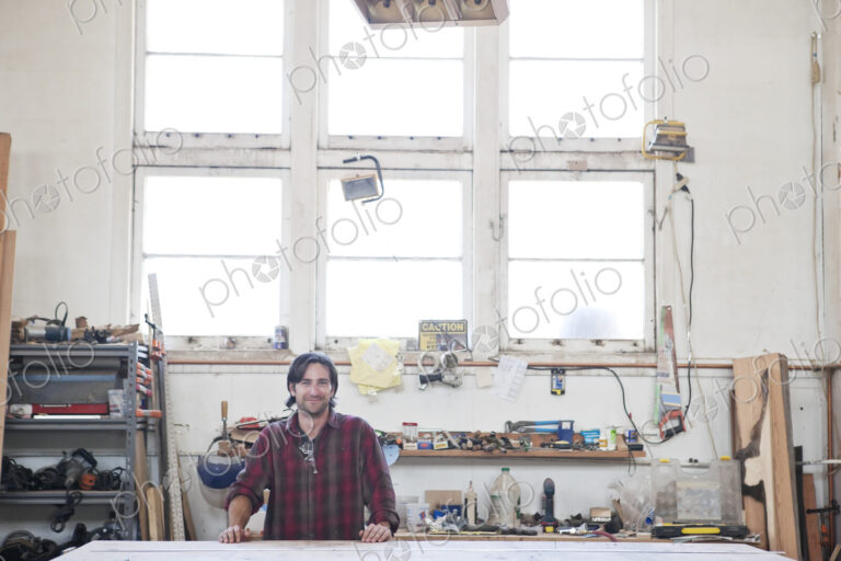 View of a caucasian man factory worker wearing safetly glasses in a woodworking factory.