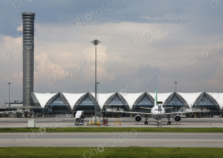 View of a modern airport terminal in Bangkok, a tall tower and aircraft.