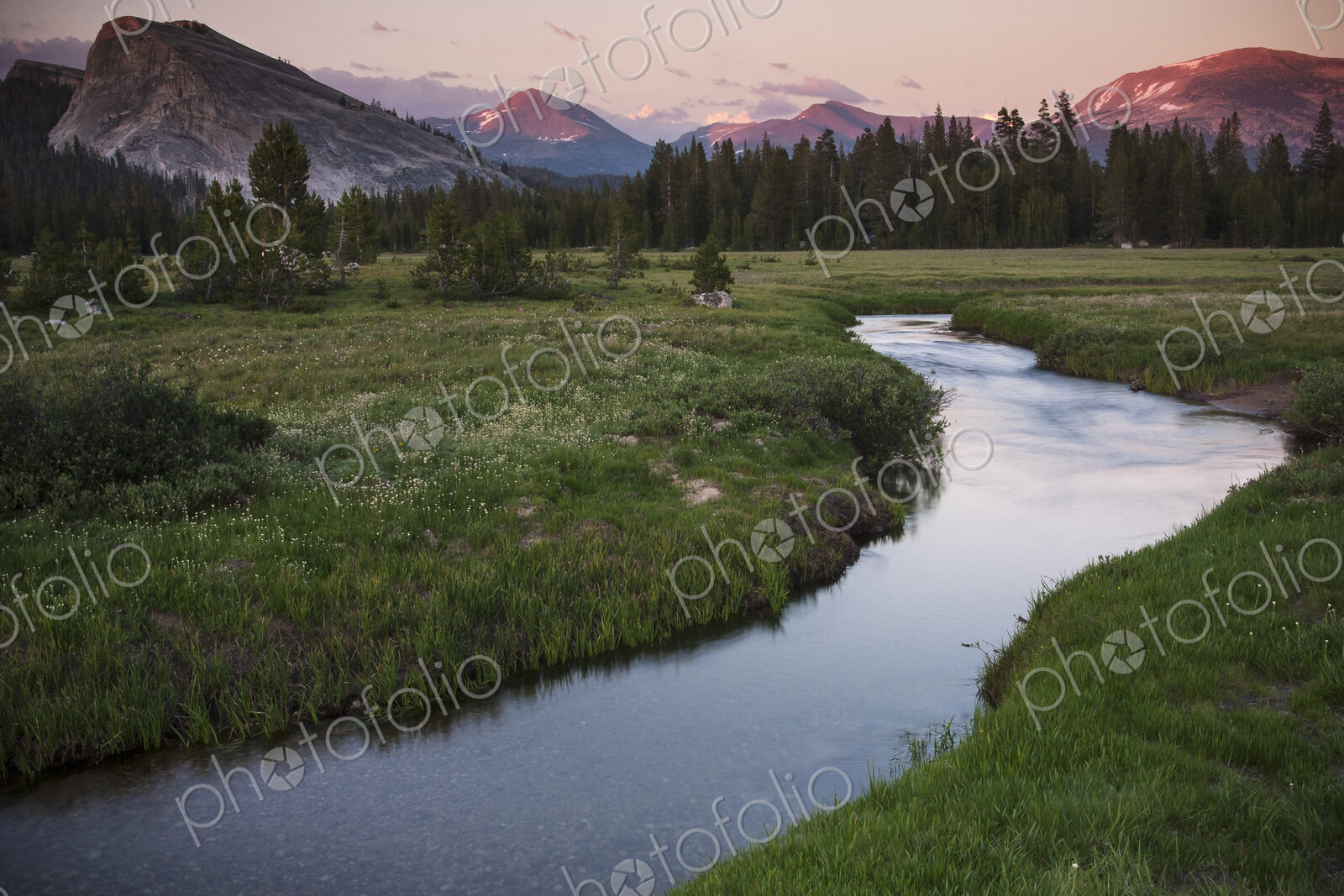 View of a river running through grassland in a valley in California.