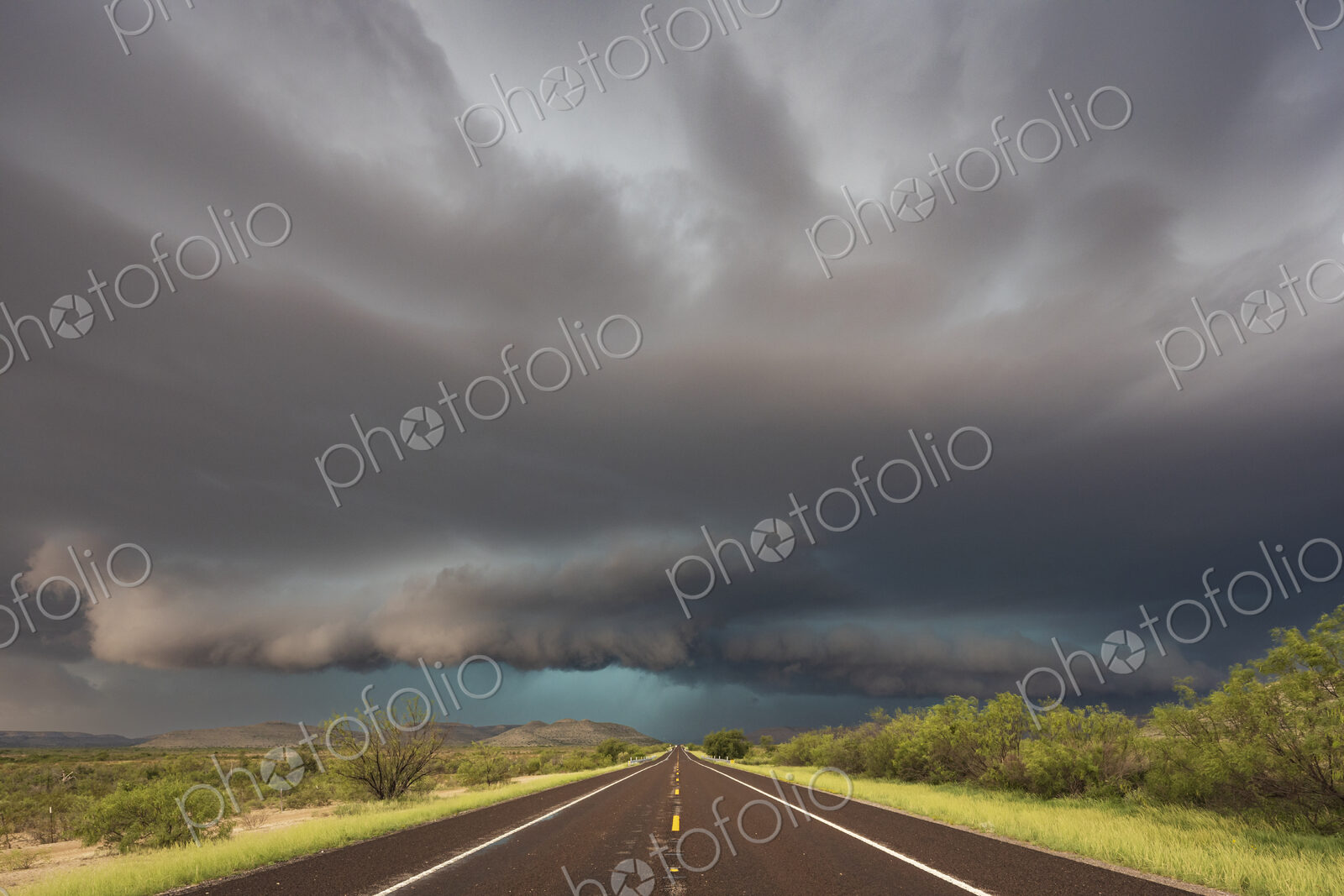 View of a road reaching the horizon, with black storm clouds above the road, the Texas…