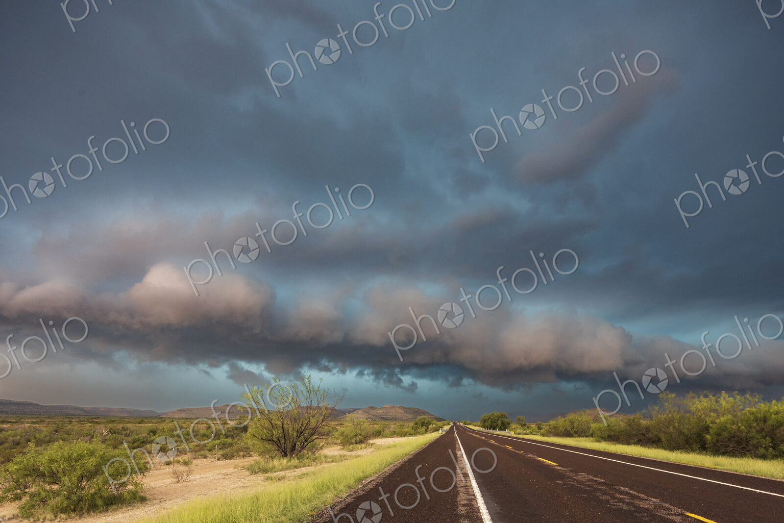 View of a road reaching the horizon, with black storm clouds above the road, the Texas…