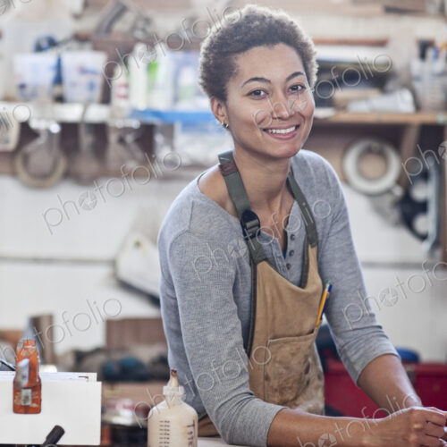 View of a smiling black woman factory worker at her work station in a woodworking factory.