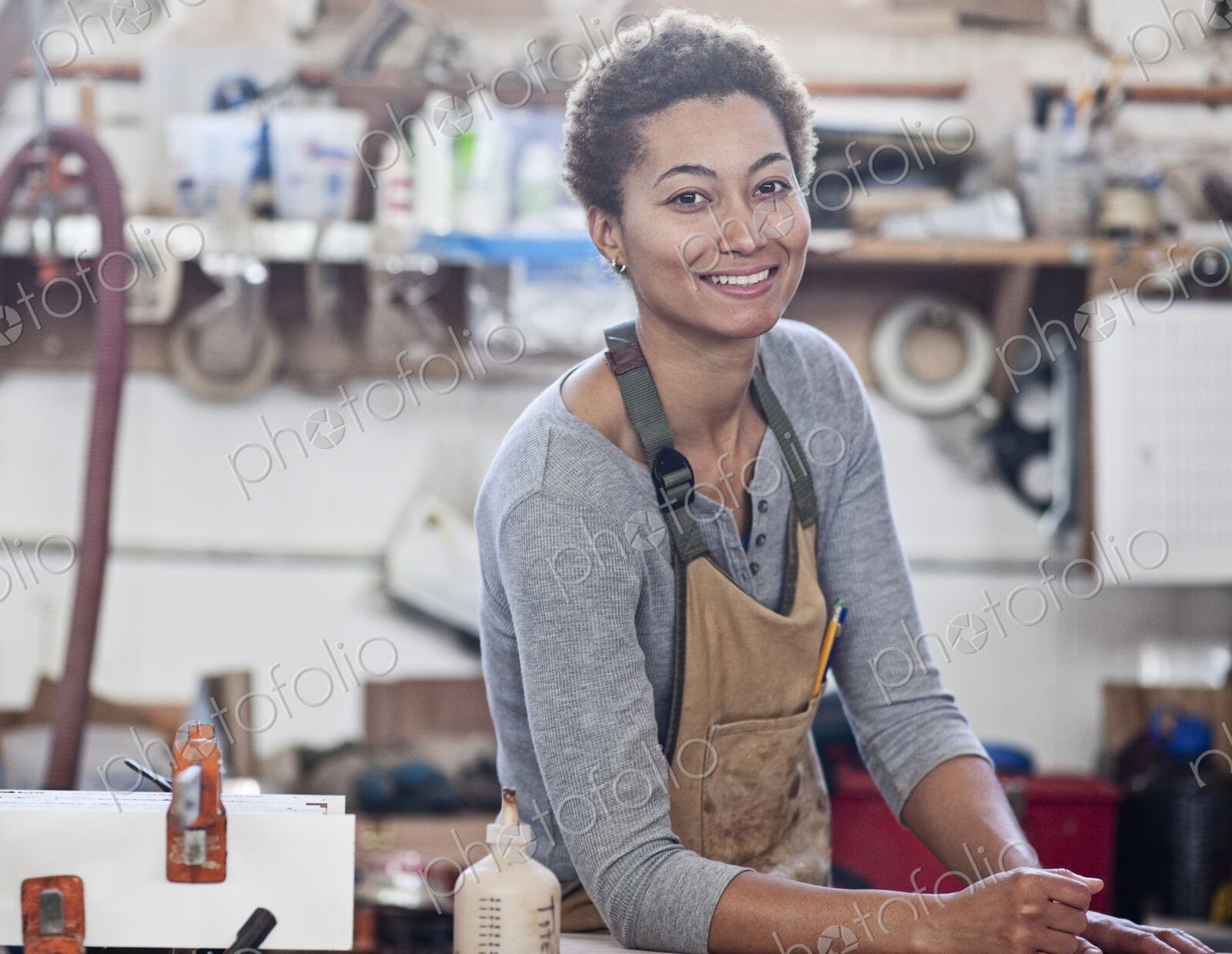 View of a smiling black woman factory worker at her work station in a woodworking factory.