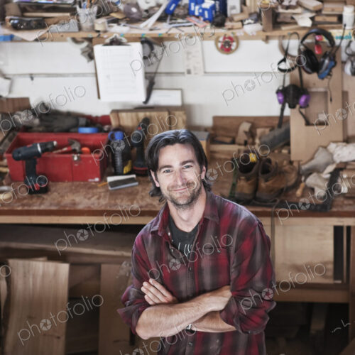 View of a smiling caucasian man factory worker at his work station in a woodworking… View of a smiling caucasian man factory worker at his work station in a woodworking…