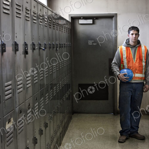 View of a young caucasian factory worker wearing a safety vest and standing next to…
