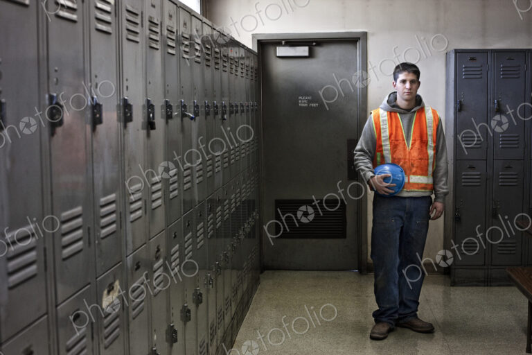 View of a young caucasian factory worker wearing a safety vest and standing next to…