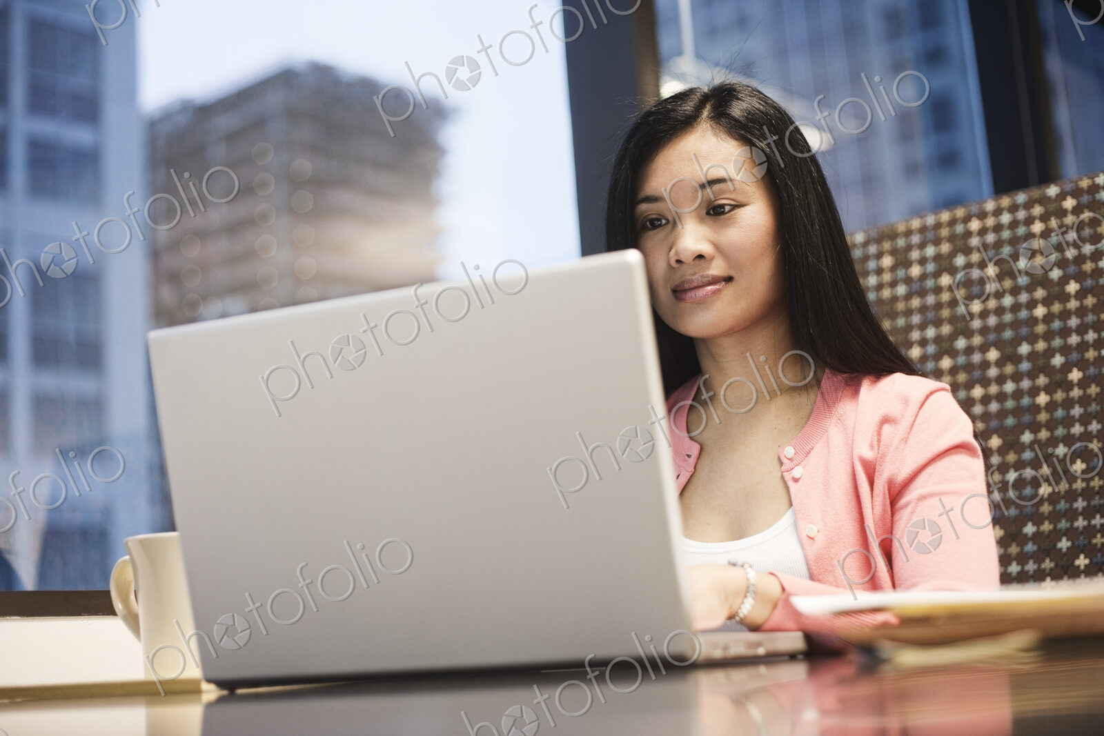 View of an Asian businesswoman working on a laptop computer in her office with a view…