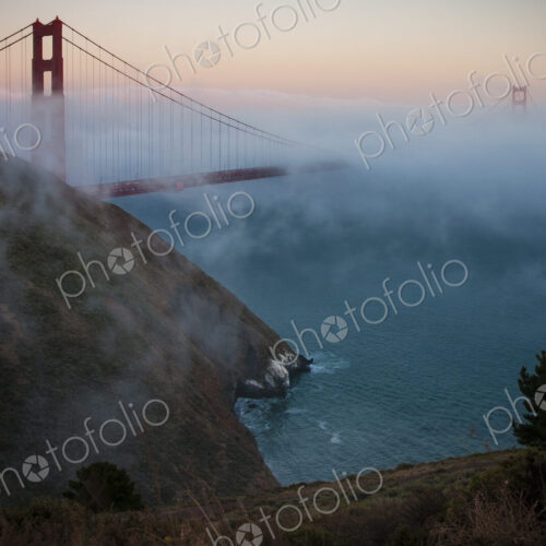 View of the Golden Gate Bridge in San Francisco at sunset in fog. View of the Golden Gate Bridge in San Francisco at sunset in fog.