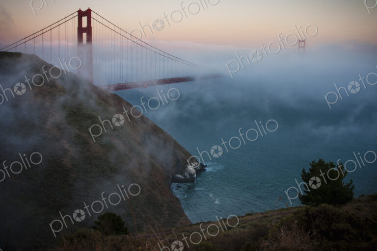 View of the Golden Gate Bridge in San Francisco at sunset in fog.
