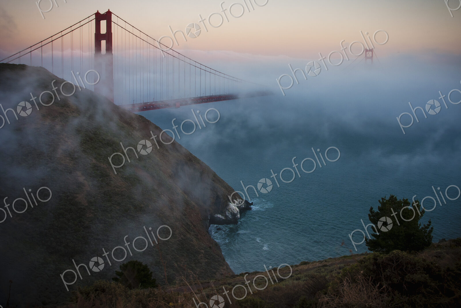 View of the Golden Gate Bridge in San Francisco at sunset in fog.
