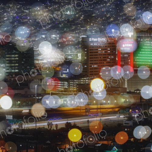 View of the lights of a city at night, blurred pinpoints of light, colours and shapes.