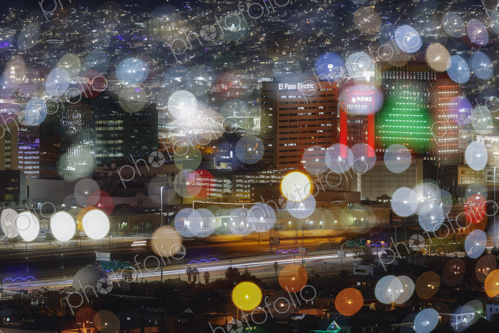 View of the lights of a city at night, blurred pinpoints of light, colours and shapes.