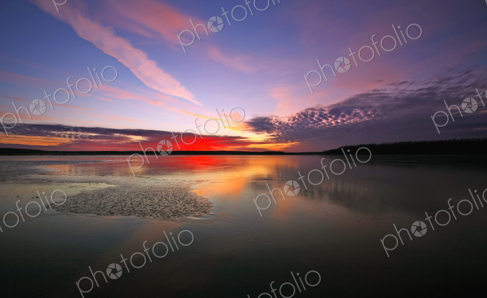 View of the sky and cloud patterns reflected in the frozen surface of a lake.