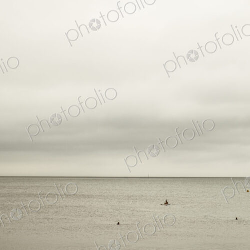 View out to sea, and people swimming and jumping off the harbour wall.
