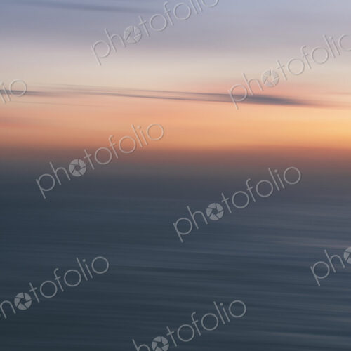 View out to sea over the ocean at dusk, the sunset light on the horizon and calm…
