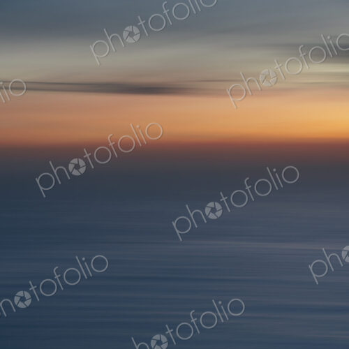 View out to sea over the ocean at dusk, the sunset light on the horizon and calm…