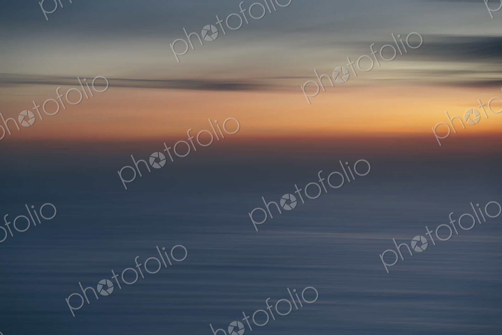 View out to sea over the ocean at dusk, the sunset light on the horizon and calm…