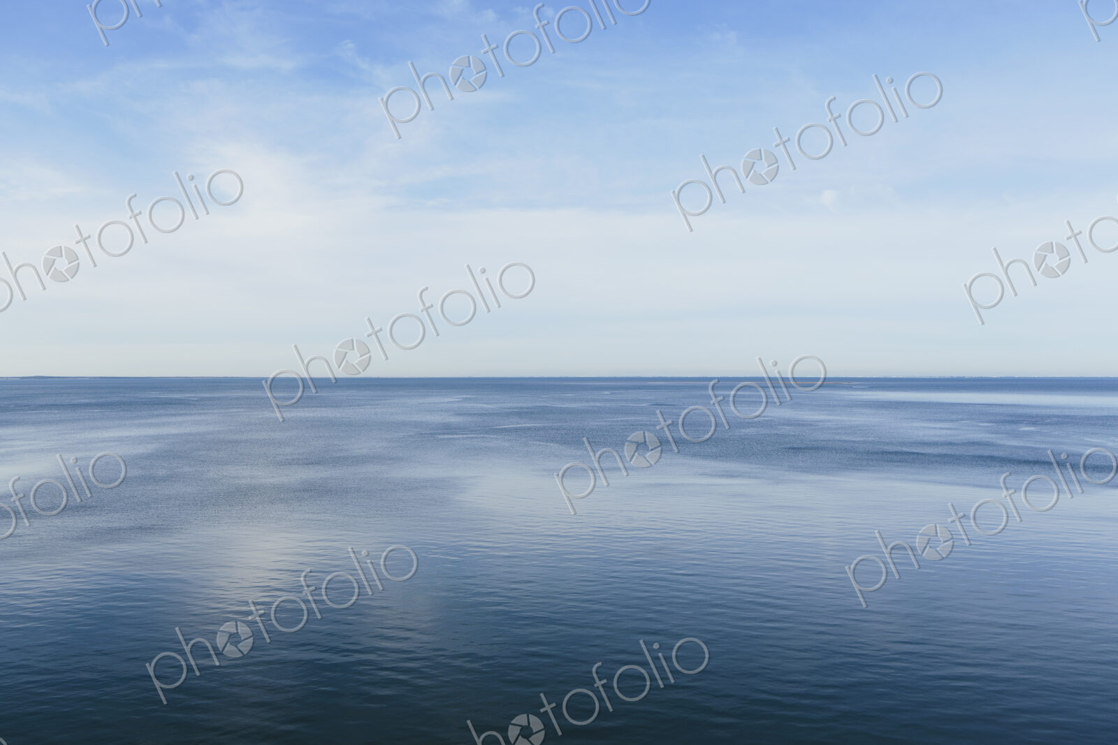 View out to the open sea from the coast. Flat calm water surface.