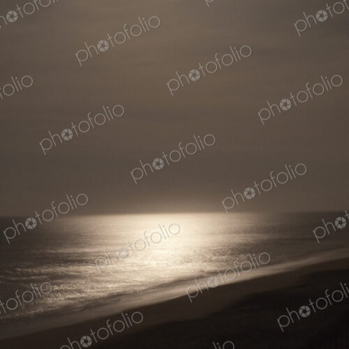 View over the water from shore at night, reflection of the moon on the water. View over the water from shore at night, reflection of the moon on the water.