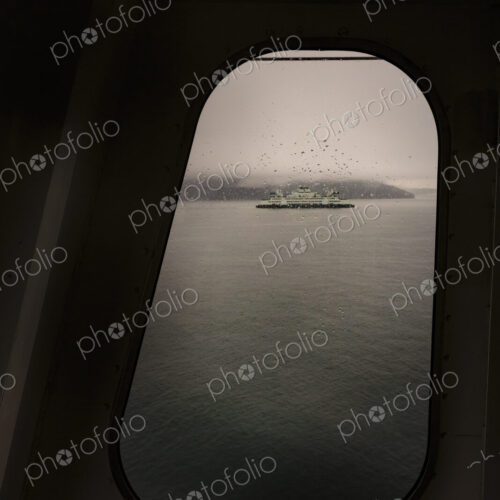 View through a ferry porthole window of the grey stormy weather in the San Juan…