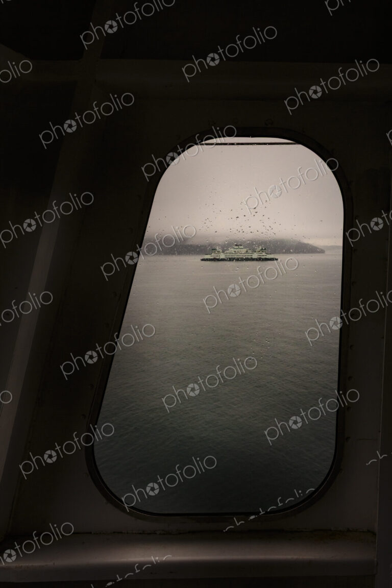 View through a ferry porthole window of the grey stormy weather in the San Juan…