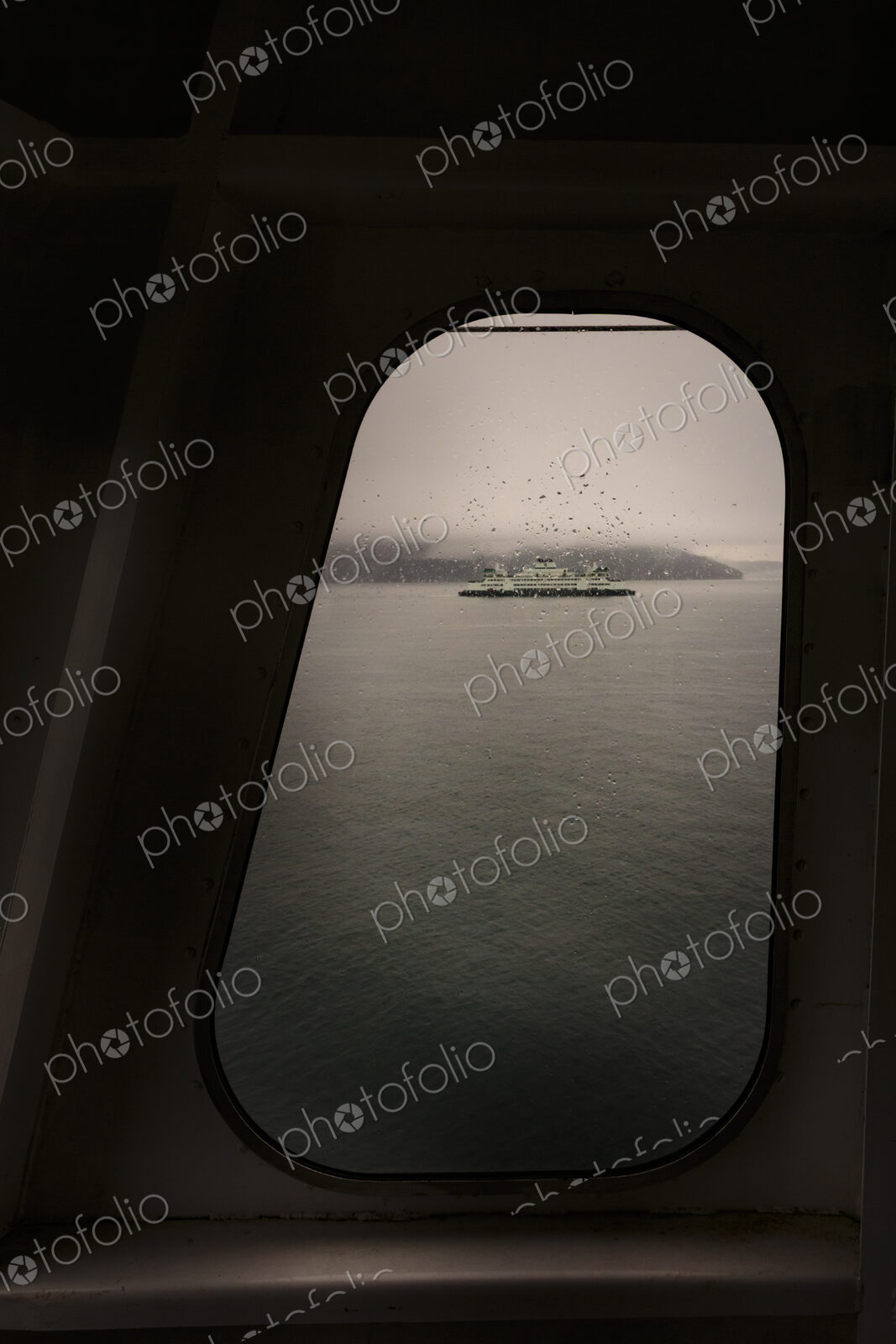 View through a ferry porthole window of the grey stormy weather in the San Juan…