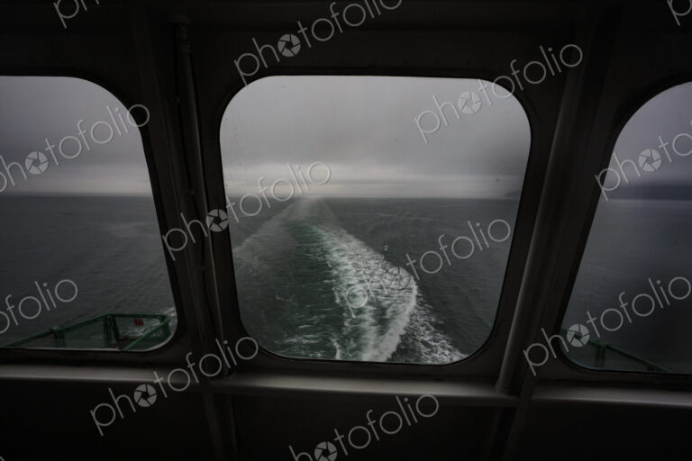 View through a ferry porthole window of the grey stormy weather in the San Juan…