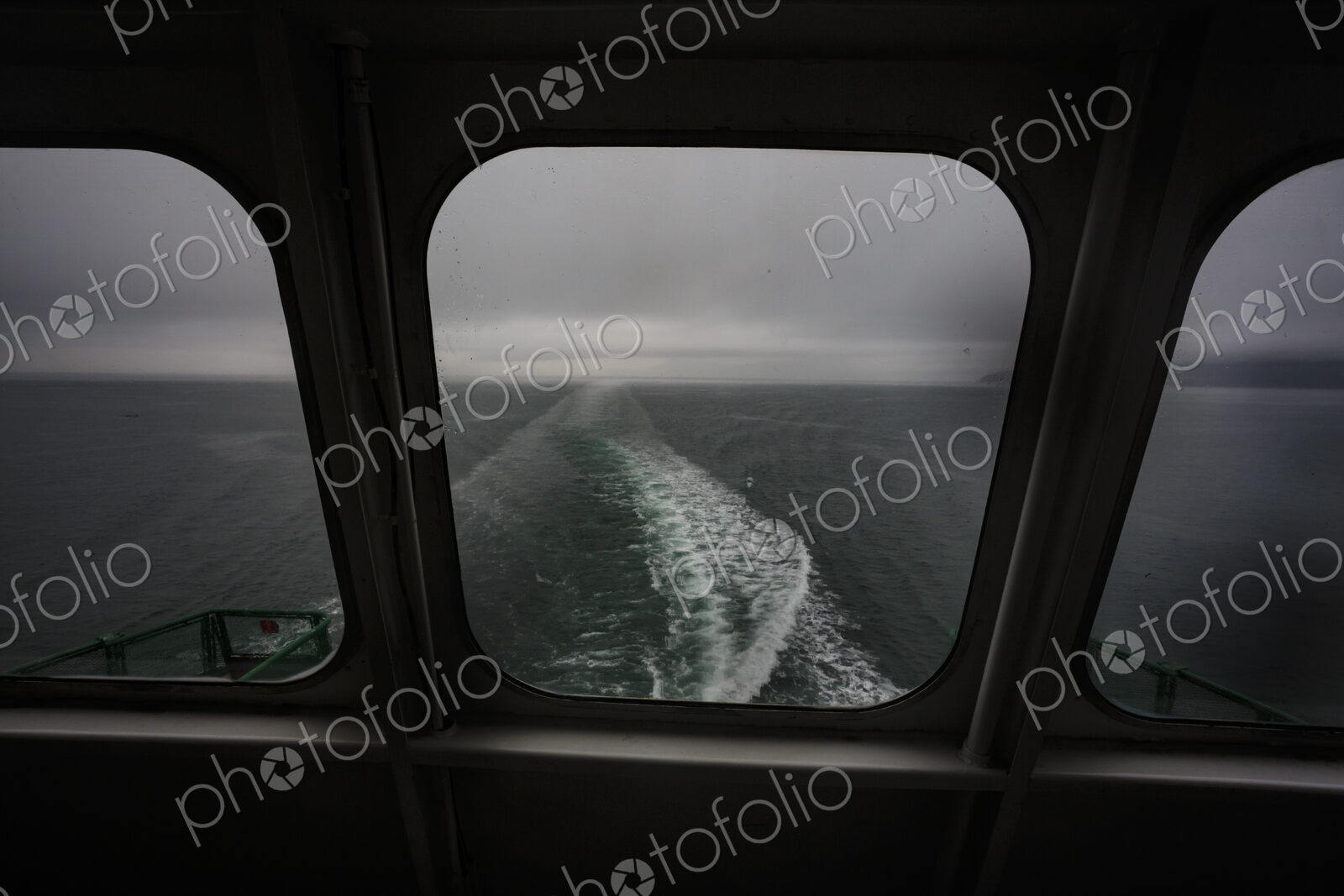 View through a ferry porthole window of the grey stormy weather in the San Juan…