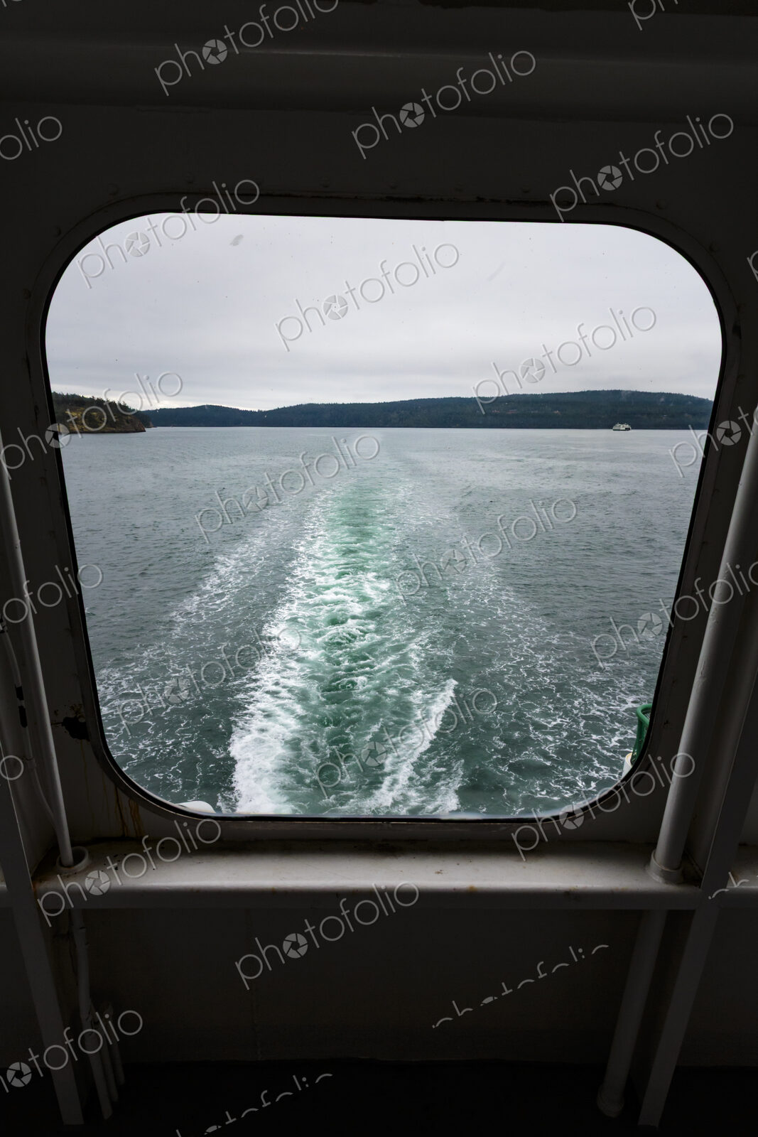 View through a ferry porthole window of the grey stormy weather in the San Juan…