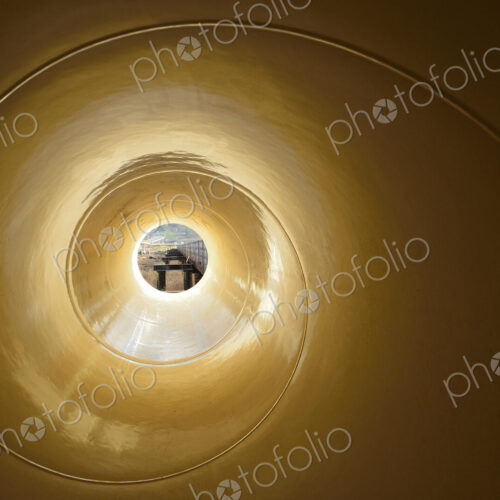 View through a narrow object with a spiral pattern to a street scene.