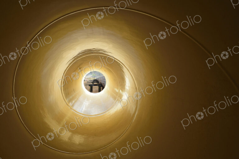 View through a narrow object with a spiral pattern to a street scene.