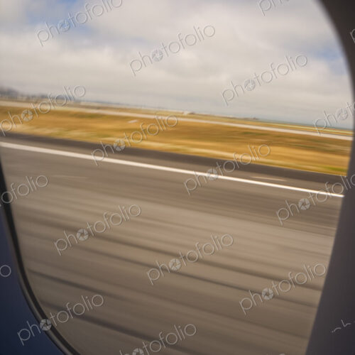 View through an aircraft window of the runway during take off.