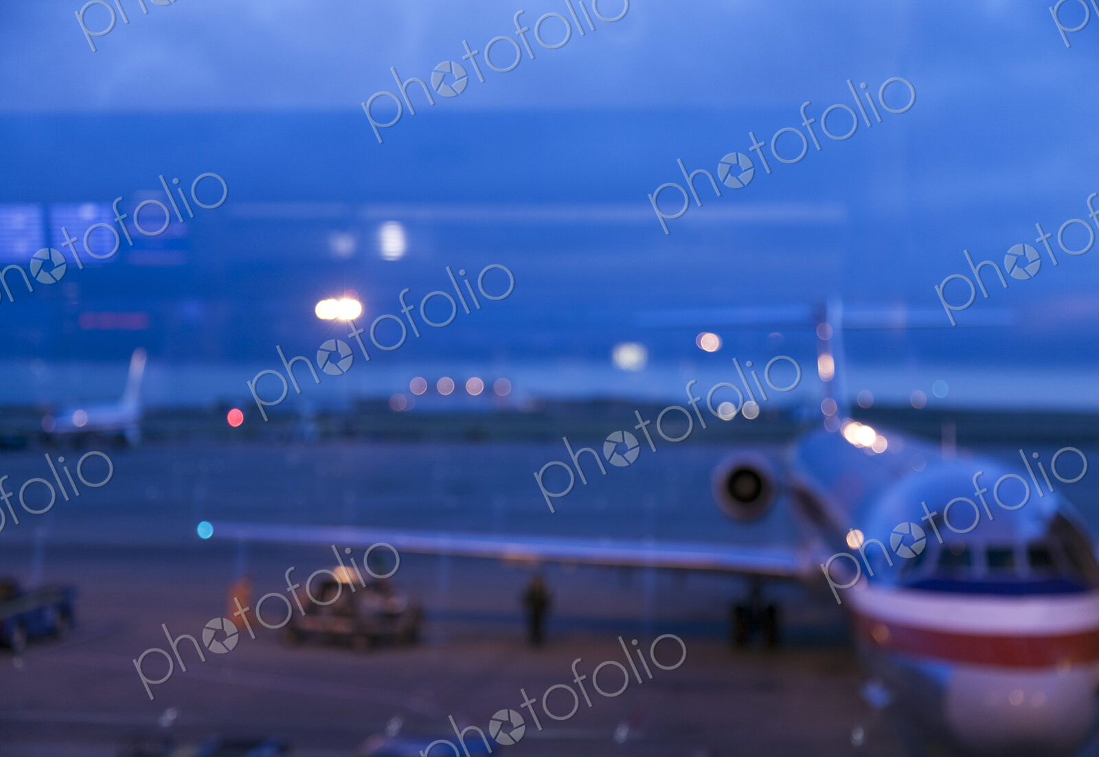 View through an airport window of buildings, of the traffic on the airport runways and…
