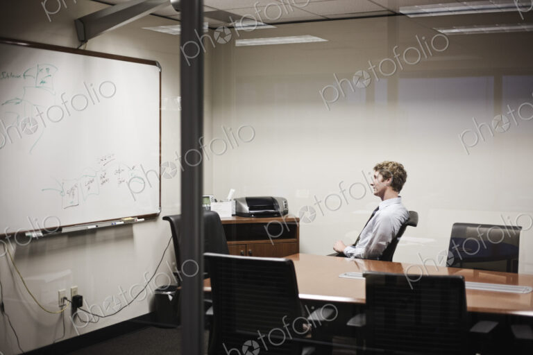 View through glass of a businessman working on a project in an office conference room.