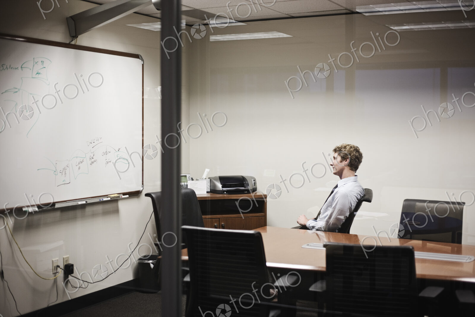 View through glass of a businessman working on a project in an office conference room.