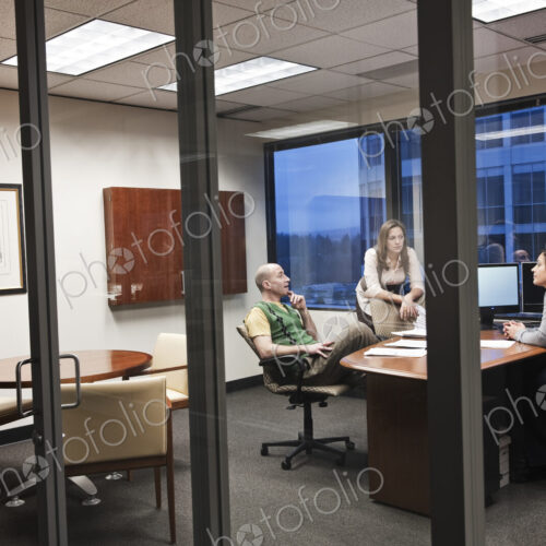 View through the doorway of three peole working on a project in an office. View through the doorway of three peole working on a project in an office.