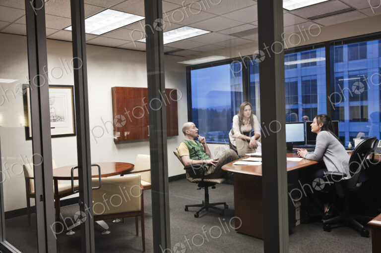 View through the doorway of three peole working on a project in an office.
