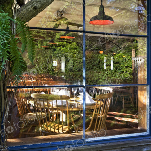 View through window of the empty dining area in a restaurant, reflection in the glass.