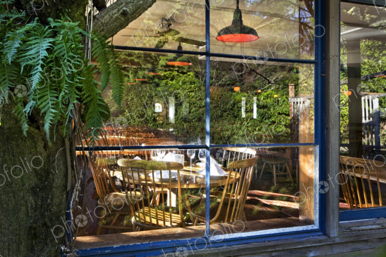 View through window of the empty dining area in a restaurant, reflection in the glass.