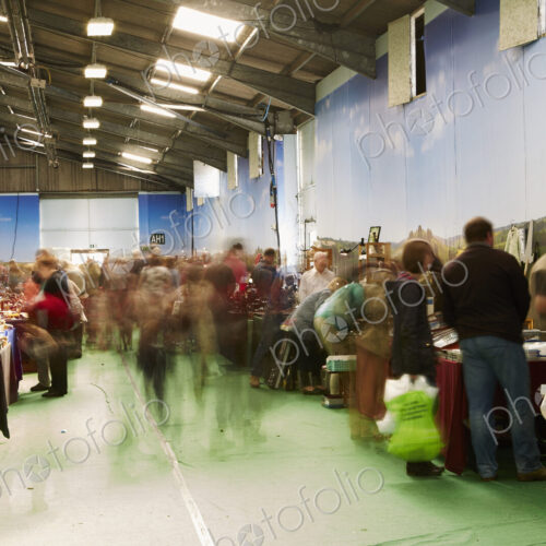 Visitors browsing items at stalls at a busy flea market.