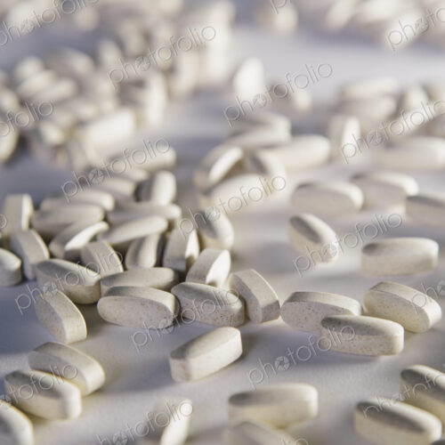 Vitamin C supplements, white oval tablets taken for health reasons. Spread out on a…