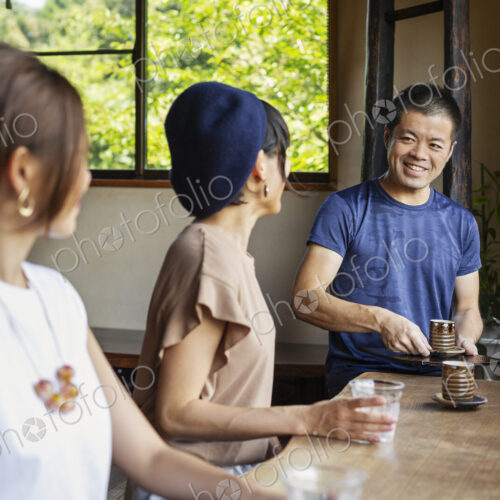 Waiter serving two Japanese women sitting at a table in a Japanese restaurant. Waiter serving two Japanese women sitting at a table in a Japanese restaurant.