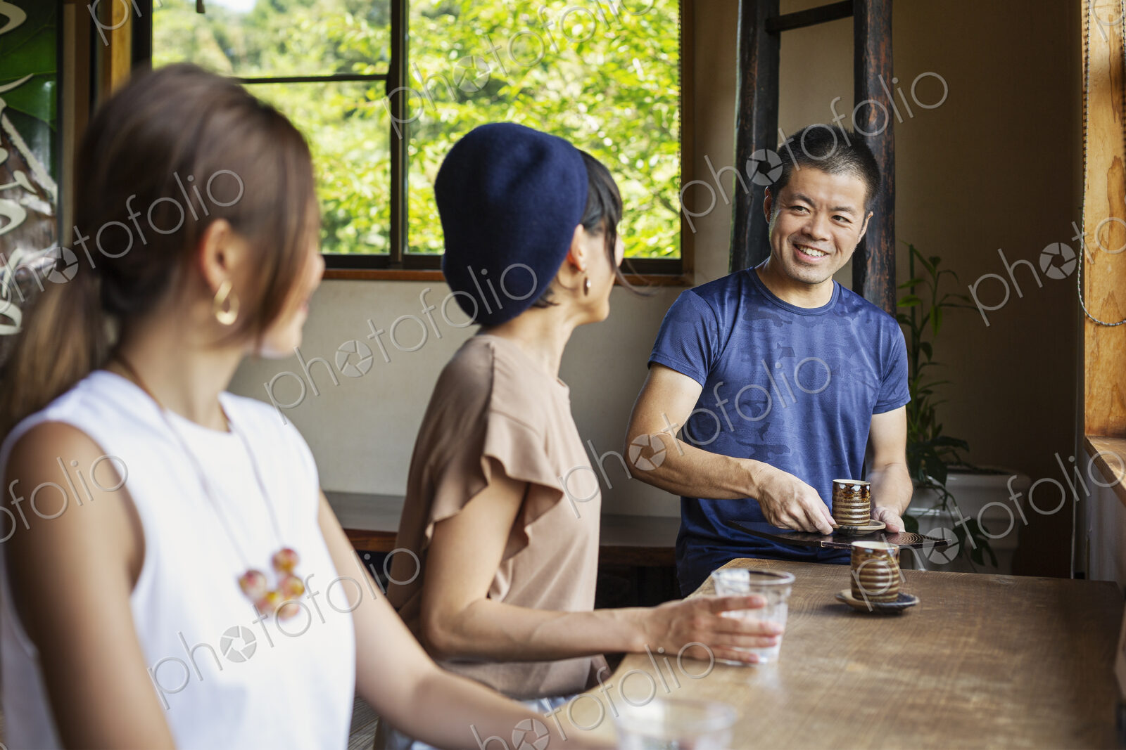 Waiter serving two Japanese women sitting at a table in a Japanese restaurant.