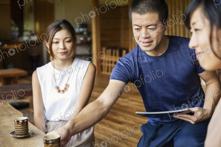 Waiter serving two Japanese women sitting at a table in a Japanese restaurant.