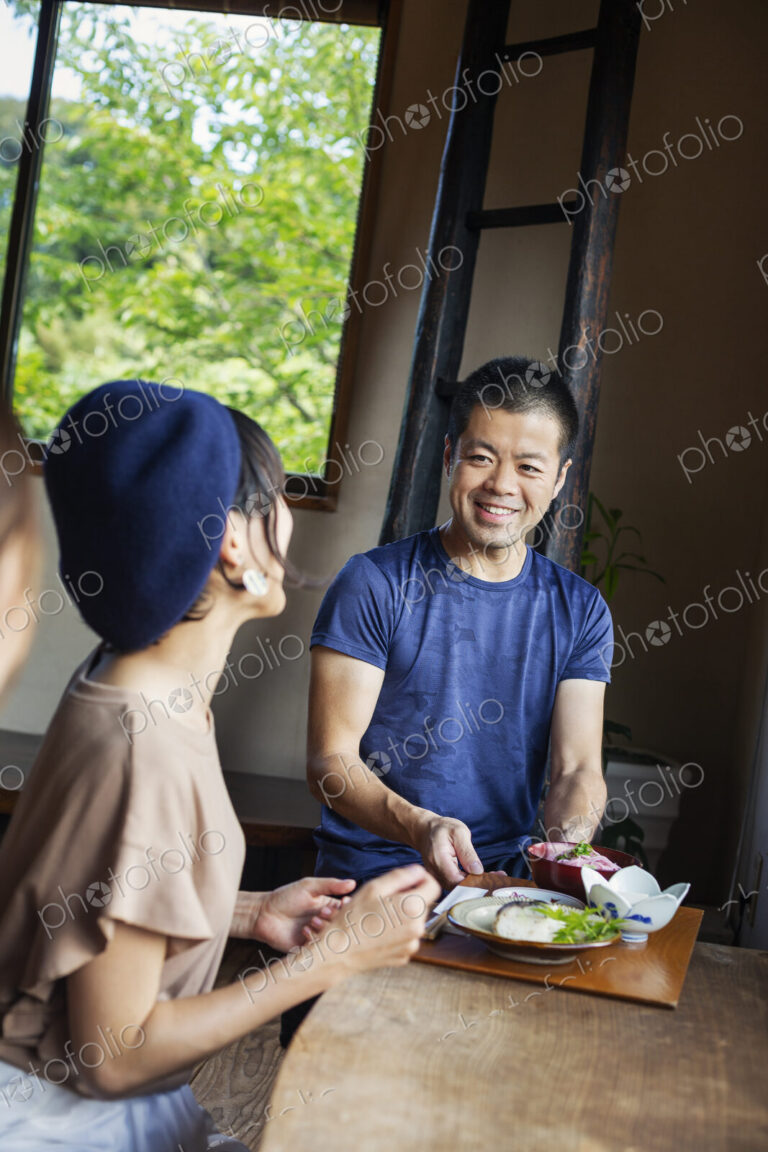 Waiter serving two Japanese women sitting at a table in a Japanese restaurant.