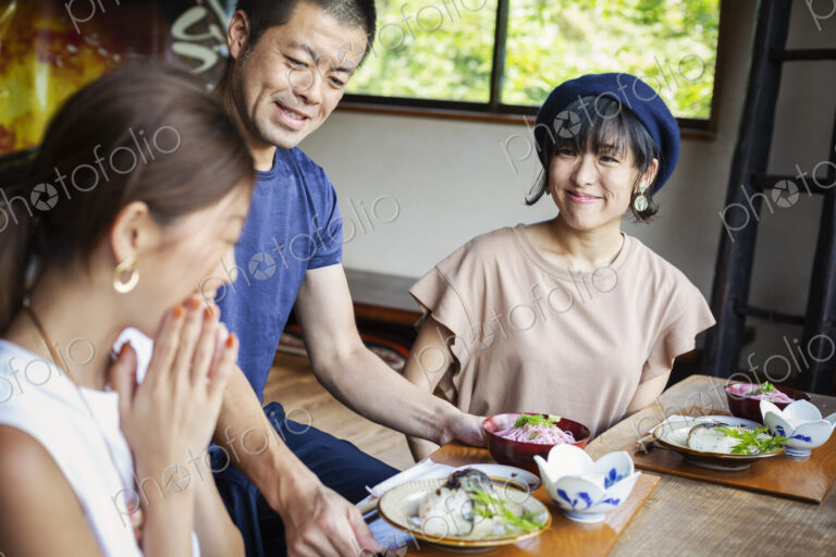 Waiter serving two Japanese women sitting at a table in a Japanese restaurant.