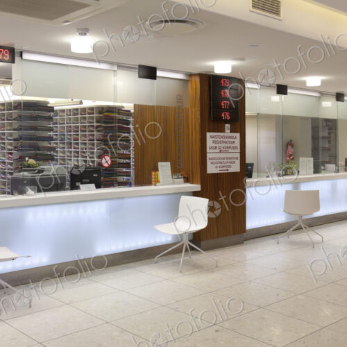 Waiting area and reception desk at a modern hospital, with signs and electronic display Waiting area and reception desk at a modern hospital, with signs and electronic display