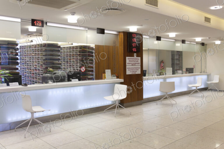 Waiting area and reception desk at a modern hospital, with signs and electronic display