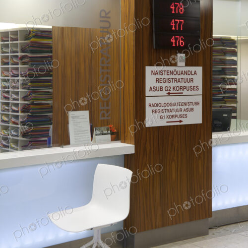Waiting area and reception desk at a modern hospital, with signs and electronic display Waiting area and reception desk at a modern hospital, with signs and electronic display
